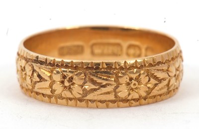 Lot 27 - An 18ct wedding band, with all around engraved...